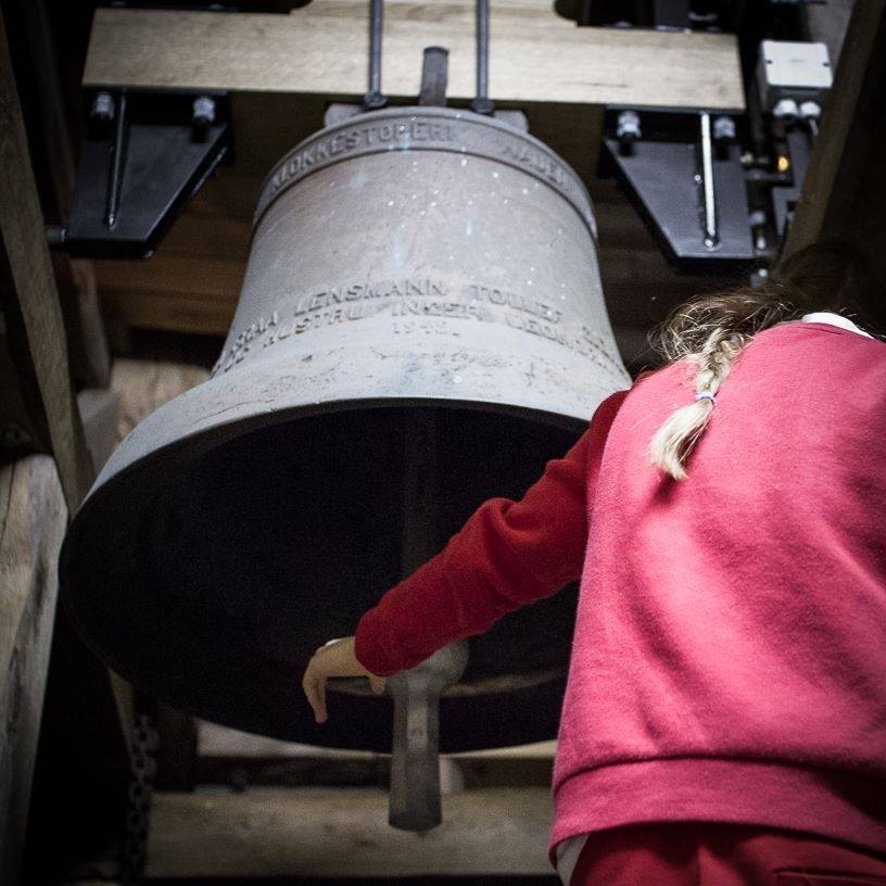 Jente som slår med en av klokkene i Bjerkreim kirkes tårn
